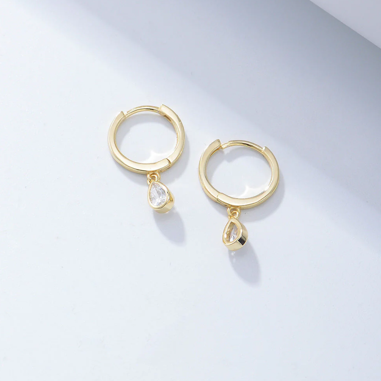 Each earring features a pear-shaped diamond simulant, beautifully bezel set for a sleek, contemporary finish that enhances sparkle while keeping the design timeless and secure. The soft drop silhouette flatters the face and adds a subtle glow, making these earrings perfect for both day wear and evening elegance.