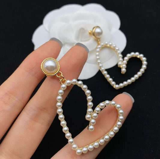 Heart-shaped dangle earrings featuring lustrous pearls