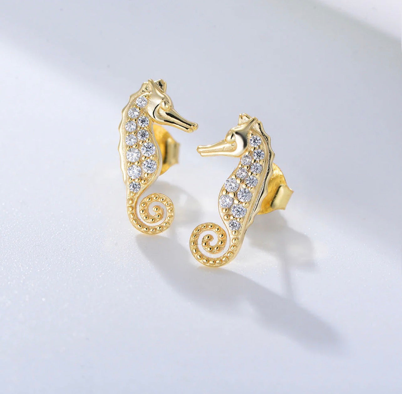 Crafted from premium 925 sterling silver and finished with 18-carat yellow gold vermeil, The Seahorse Studs offer lasting shine, durability, and a luxurious feel. Their petite size and smooth contours make them effortless to wear, while the symbolic seahorse design adds character and meaning without overpowering your look.

Lightweight, hypoallergenic, and tarnish-resistant, The Seahorse Studs are designed for all-day comfort and long-lasting wear. Whether worn alone for a subtle coastal accent or layered w