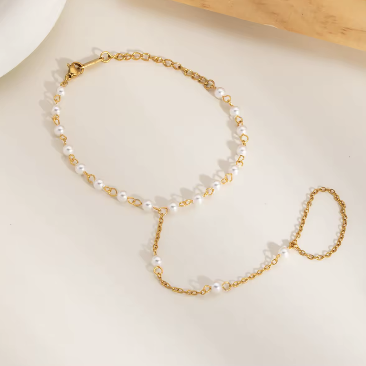 Gold-dipped stainless steel Pearly Link Bracelet featuring lustrous imitation pearls, connected by a delicate chain linking a ring and bracelet; elegant, feminine, and modern jewelry design